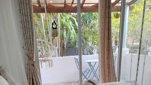 A bed with a quilted mattress, a green decorative pillow, and rolled towels. - Luana Villas (Ko Lanta)