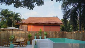 A backyard with a swimming pool, wooden deck, outdoor furniture, and a bamboo fence. - Luana Villas (Ko Lanta)