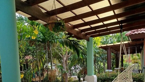 A covered outdoor seating area with a table and chairs, surrounded by lush greenery and a hanging hammock. - Luana Villas (Ko Lanta)