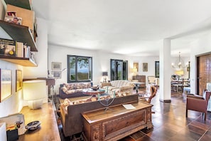 A spacious living room with a sofa, armchairs, a wooden coffee table, and a bookshelf. - Three Lakes Villa Varese (Buguggiate)