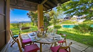 Une terrasse extérieure avec une table dressée pour le repas, entourée de chaises, et offrant une vue sur un paysage montagneux.