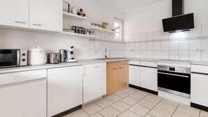 Eine moderne Küche mit weißen Schränken, einem Geschirrspüler, einer Mikrowelle, einer Kaffeemaschine und einem Herd.