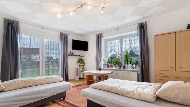 Ein Zimmer mit zwei Betten, einem Fernseher, einem Tisch und einem Fenster mit Blick.