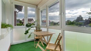 Ein Zimmer mit Holztisch und Stühlen, großen Fenstern und Teppichboden aus Kunstgrün.