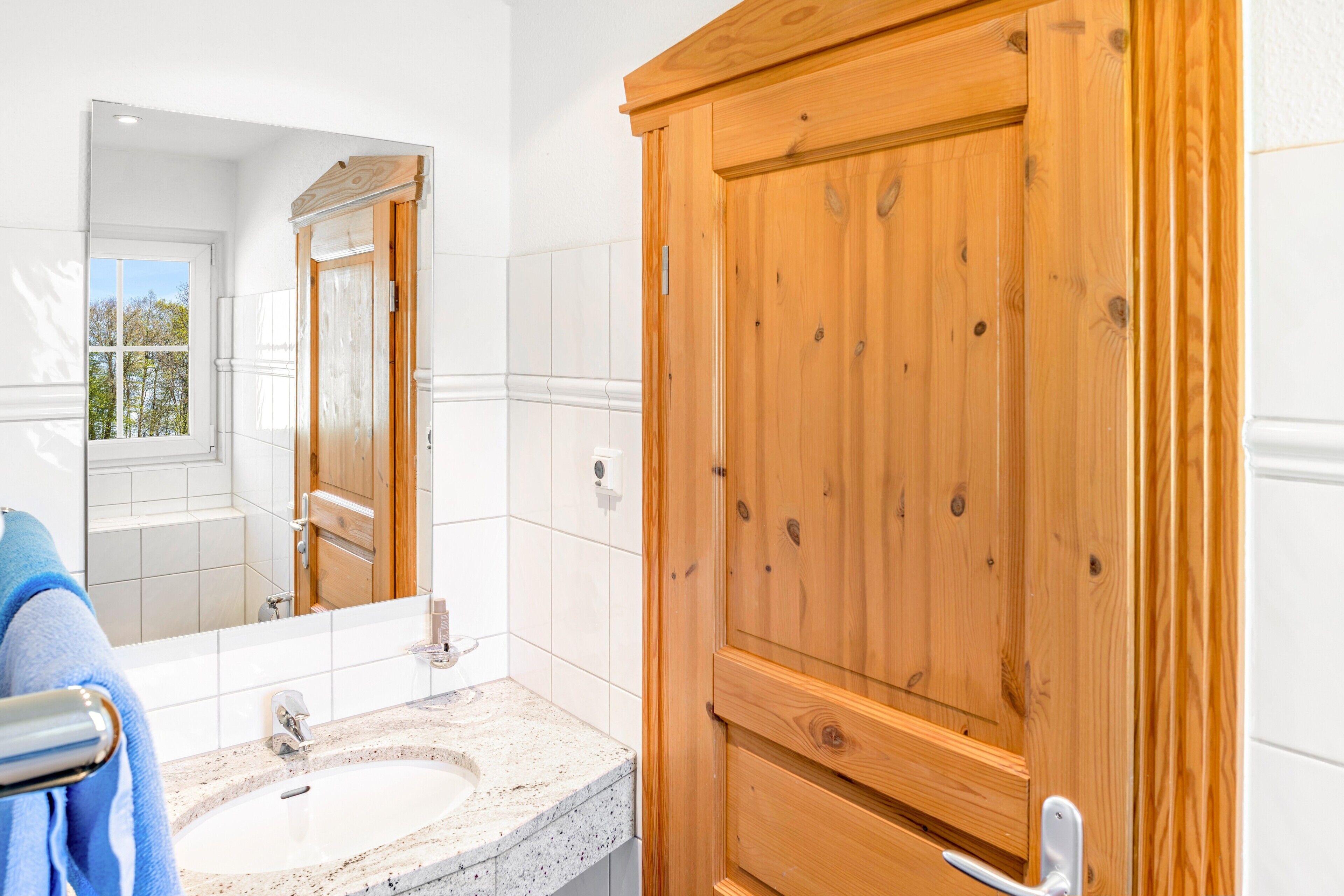 Een badkamer met een houten wastafel, een wasbak en een spiegel.
