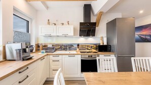 Una cocina moderna con armarios blancos, encimera de madera, horno integrado, refrigerador de acero inoxidable y una ventana con vista a un puente.