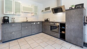 A modern kitchen with grey cabinetry, a built-in oven, and a microwave.