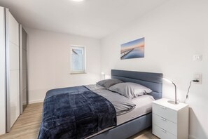 Et soveværelse med seng, sengebord, lampe og et vindue.