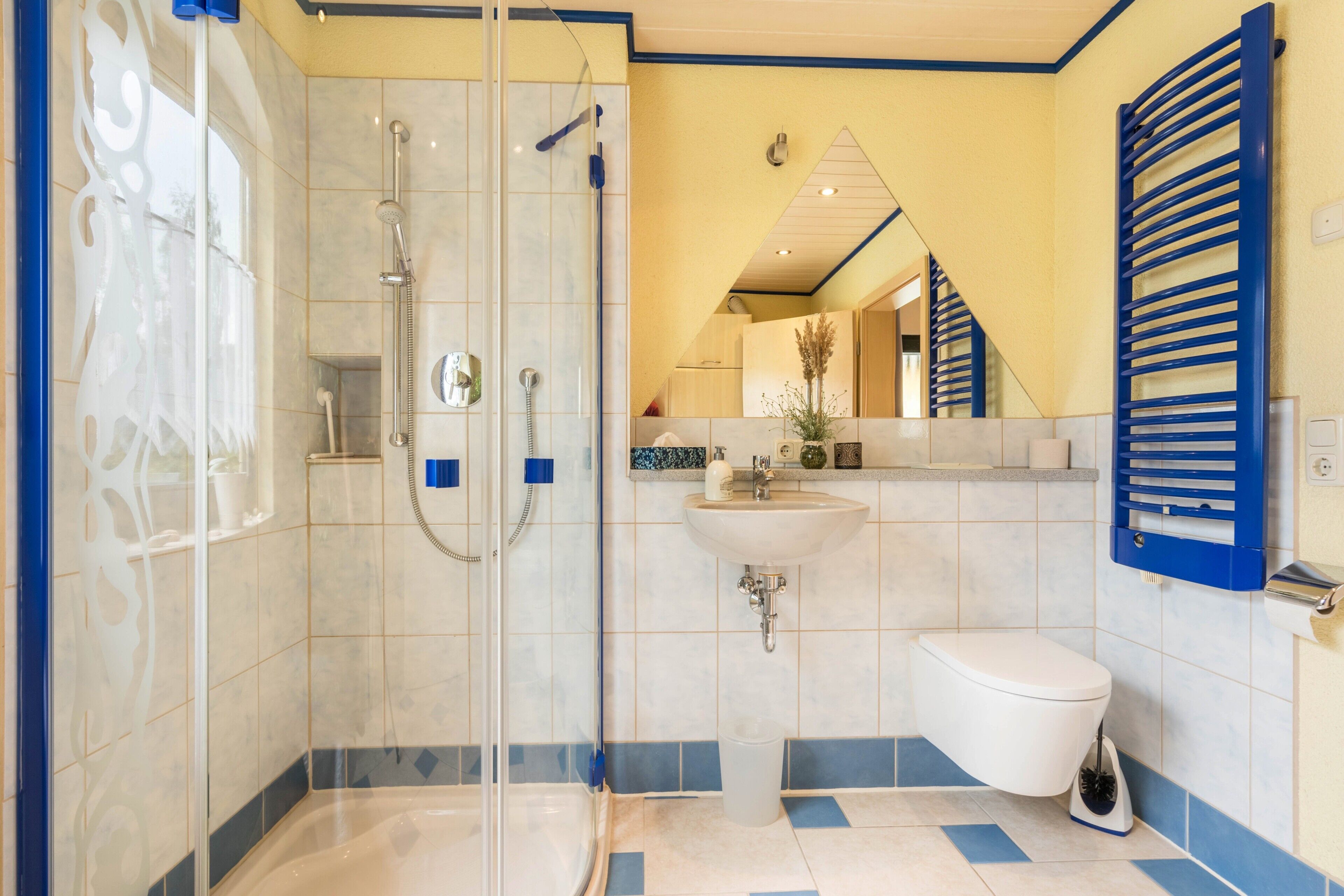 A bathroom with a glass-enclosed shower, a white sink, and a toilet.