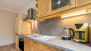 Una cocina moderna con armarios de madera, un lavamanos de acero inoxidable y una cafetera.