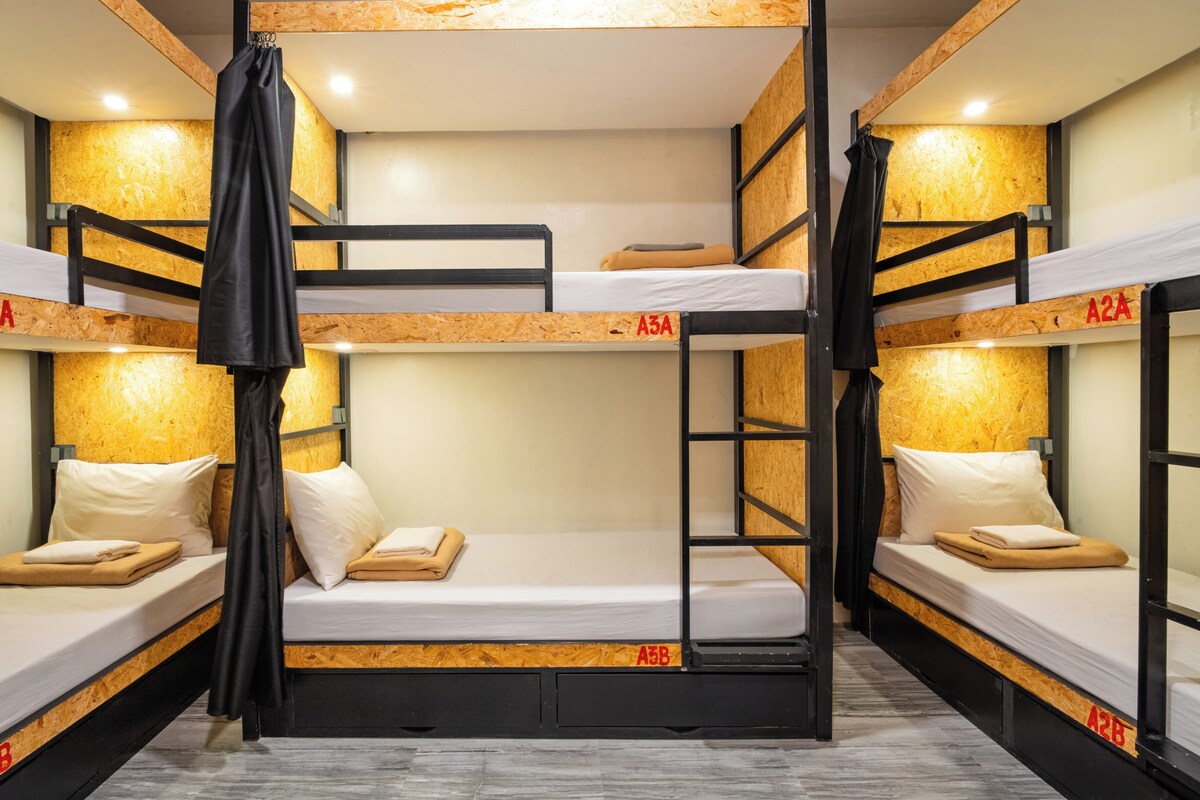 A bunk bed room with wooden headboards, white bedding, and a central ladder.