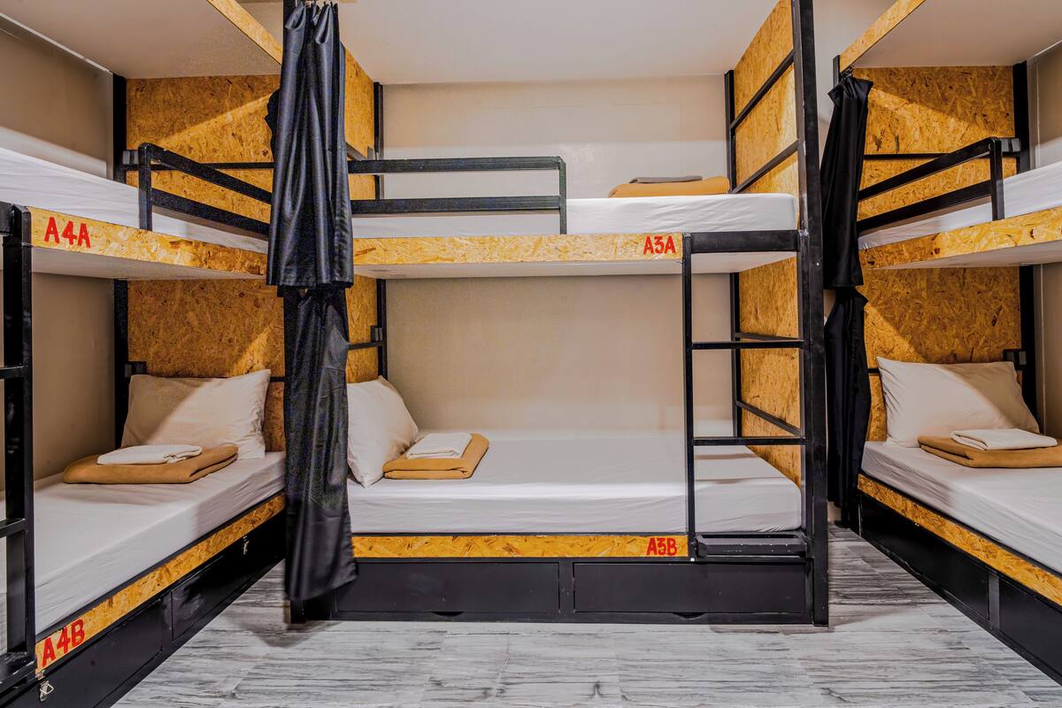 Quarto com beliches, paredes de madeira e grades de metal, identificado pelas letras A4B, A5A, A5B, A2A e A2B.
