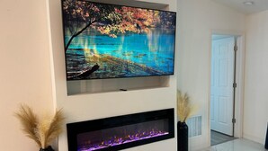 Un salon moderne avec un téléviseur à écran plat fixé au-dessus d’une cheminée.
