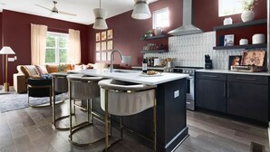 Una cocina moderna con una isla central, armarios oscuros e iluminación colgante.