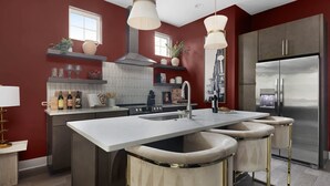 Una cocina moderna con una isla central, electrodomésticos de acero inoxidable y una pared de acento roja.