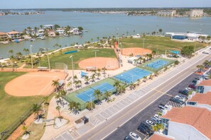 An aerial view of a sports complex with a baseball field, tennis courts, and a parking lot.