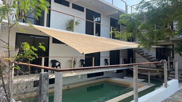 Una casa moderna de dos pisos con piscina, mobiliario exterior y un patio cubierto.
