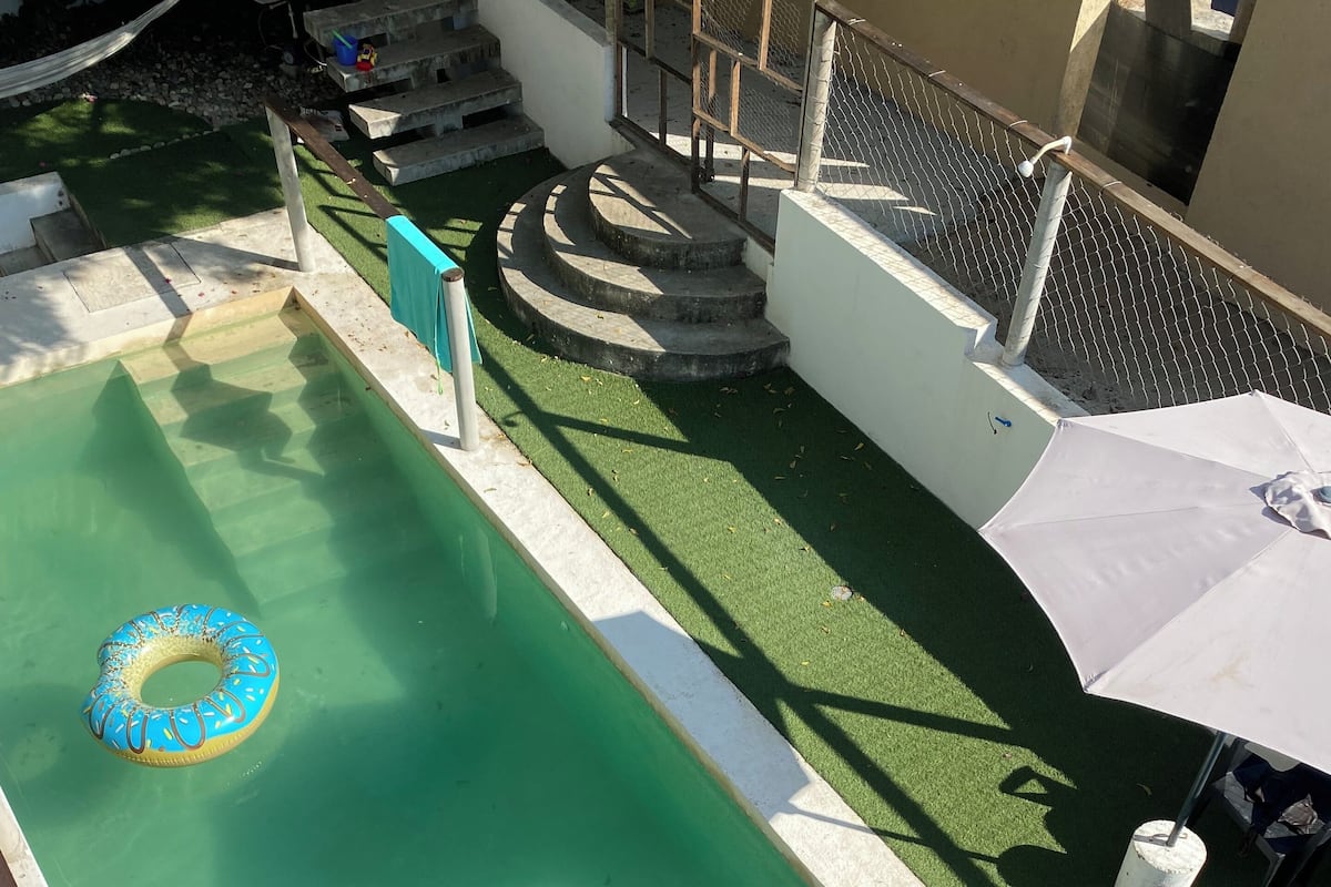 A small pool with a blue inflatable ring, steps leading to a higher level, and a white umbrella.