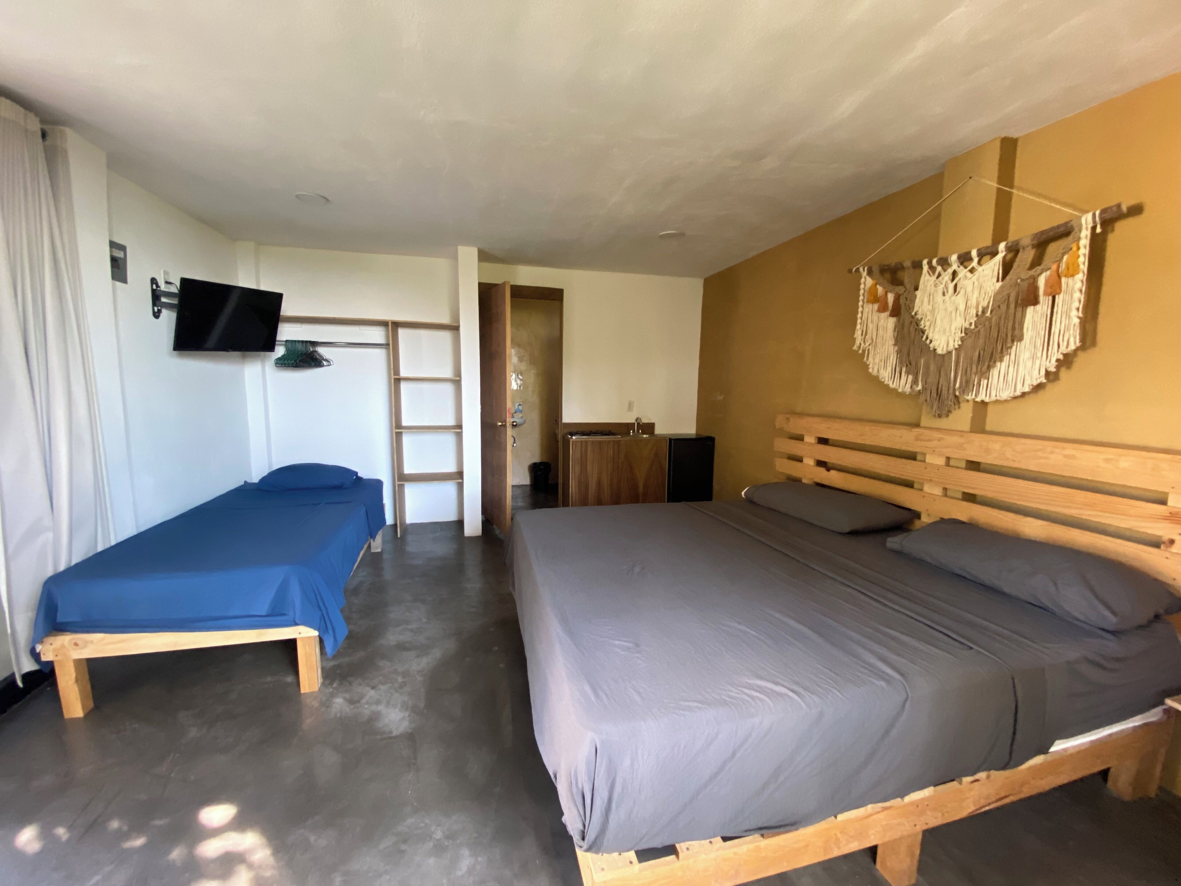 Een kamer met twee bedden, een televisie, een houten kledingkast en een kunstwerk aan de muur.
