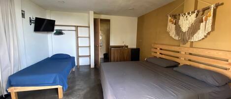 Een kamer met twee bedden, een televisie, een houten kledingkast en een kunstwerk aan de muur.