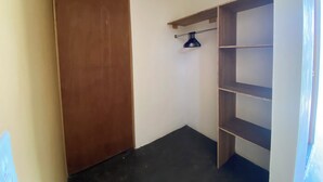 Una habitación con una puerta de madera, un perchero metálico y estanterías de madera.