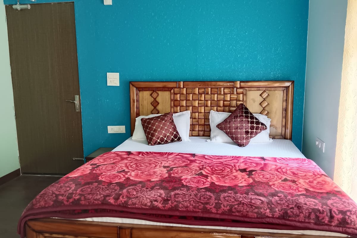 A bed with a floral-patterned bedspread, a wooden headboard, and patterned pillows.