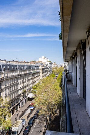 A view of a row of historic buildings with a street below, a clear sky, and a building with a balcony on the right. - Luxury#Amazing view: EiffelTower&Triumph Arc (Paris)