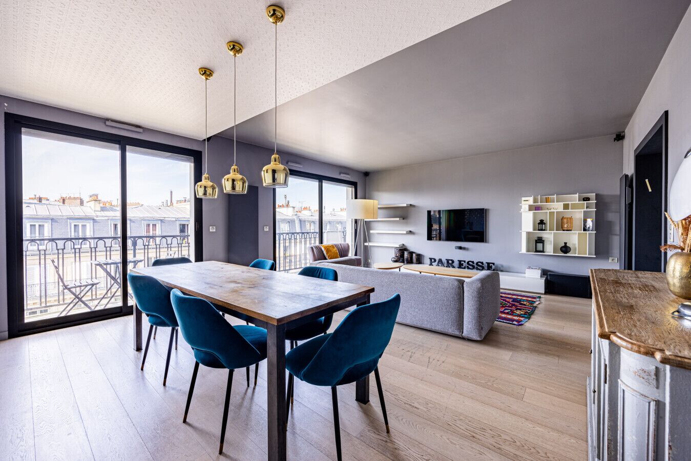 Una sala moderna con comedor, sofá, televisor y estantería.