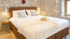 Une chambre avec un mur en pierre, une tête de lit en bois et une table de chevet avec une lampe.