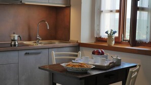 A kitchen with a sink, a kettle, and a window with lace curtains.