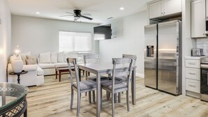 Une cuisine moderne équipée d’un réfrigérateur en acier inoxydable, d’une table à manger avec des chaises et d’un ventilateur de plafond.