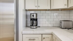 A kitchen with white cabinets, a coffee maker, and a toaster on the countertop.
