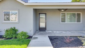 A modern house with a front door, a small porch, and a window with blinds.