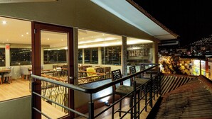 A modern hotel interior with a dining area, a staircase, and a view of the city at night. - Tikala Cusco Boutique Hotel (Cusco)