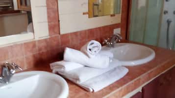 Ein Badezimmer mit zwei Waschbecken, einem Spiegel und einer Duschkabine aus Glas.