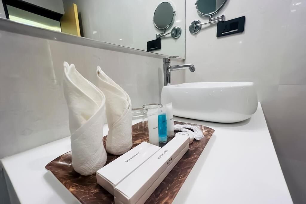 Un baño con un lavamanos blanco, dos toallas, un afeitador y una caja de cuchillas de afeitar.