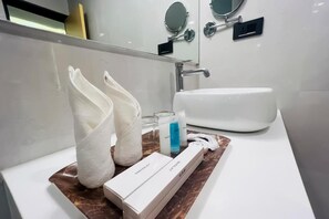 A bathroom with a white sink, two towels, a razor, and a box of razor blades. - Hotel Aikawa (Sauraha)