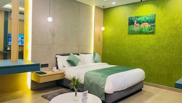 A modern hotel room with a bed, bedside table, and a green textured wall.