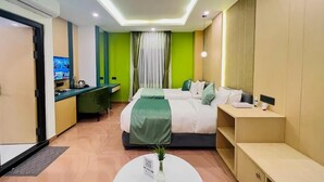 Une chambre d’hôtel moderne équipée d’un lit, d’une table de chevet et d’un bureau avec un écran d’ordinateur.