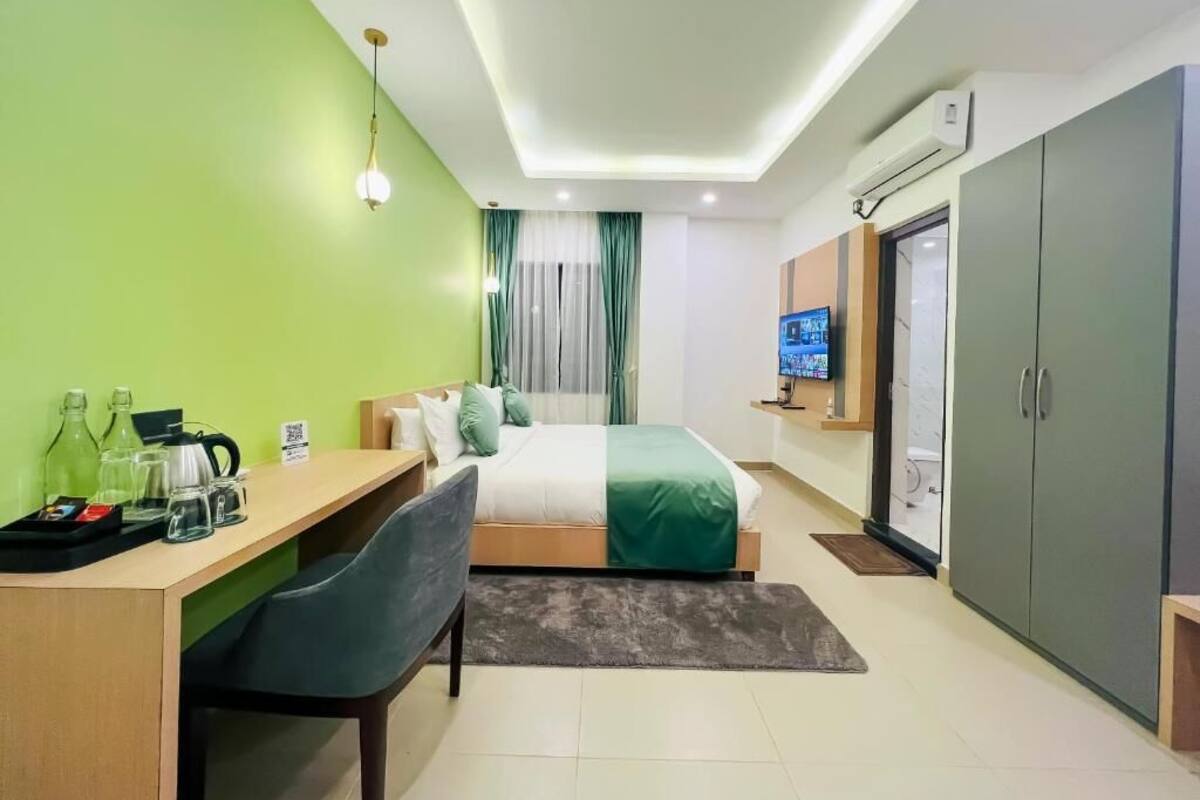 A hotel room with a bed, a desk, a chair, a television, and a wardrobe.