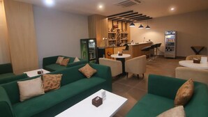 Un espace de détente moderne avec des canapés verts, un bar et un distributeur automatique.