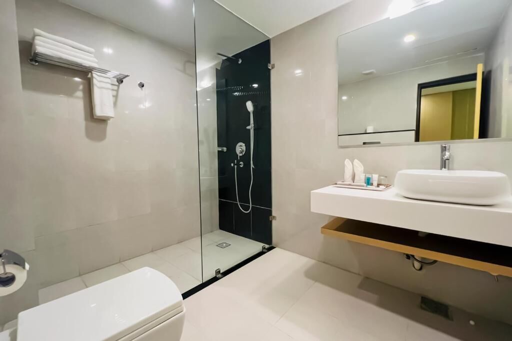 Un baño moderno con ducha de vidrio, lavamanos blanco y un inodoro.