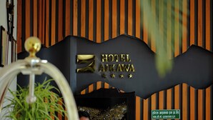 Un comptoir d’accueil avec une enseigne indiquant « HÔTEL Aikawa » et une plante décorative en premier plan.