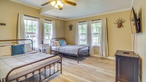 A bedroom with two metal-framed beds, a ceiling fan, and a nightstand. - Biloxi Home: Walk to Fishing & 2 Mi to Beach! (Biloxi)