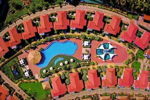 An aerial view of a resort with a central swimming pool, multiple red-roofed villas, and landscaped gardens. - Gateway Bekal (Hosdurg)