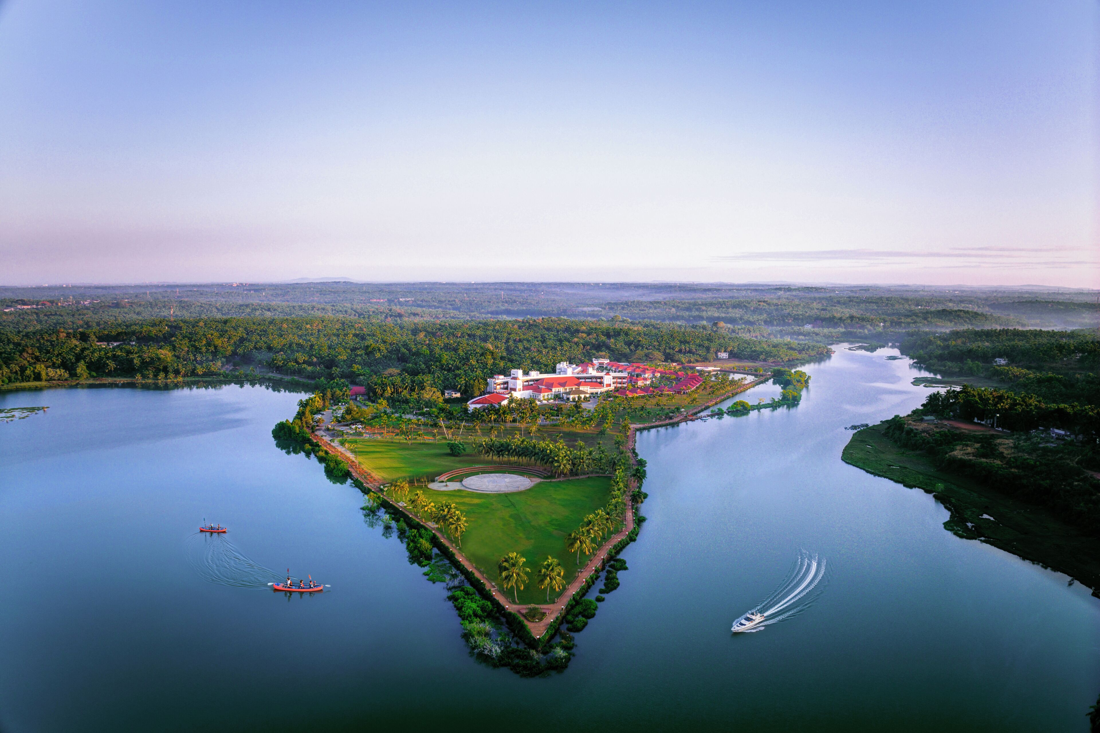 Vista aérea de un resort con campo de golf, cuerpos de agua y un edificio grande con techo rojo.