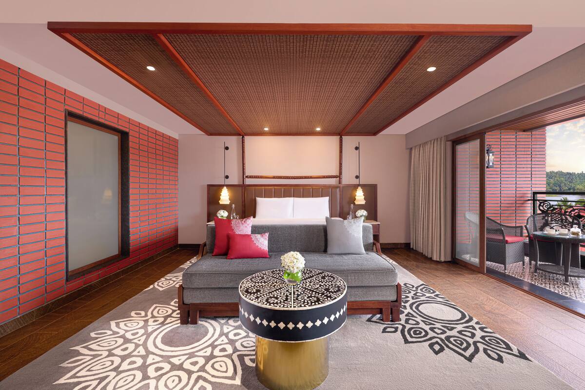 Ein modernes Schlafzimmer mit einem großen Bett, einem runden Couchtisch und Blick ins Freie.