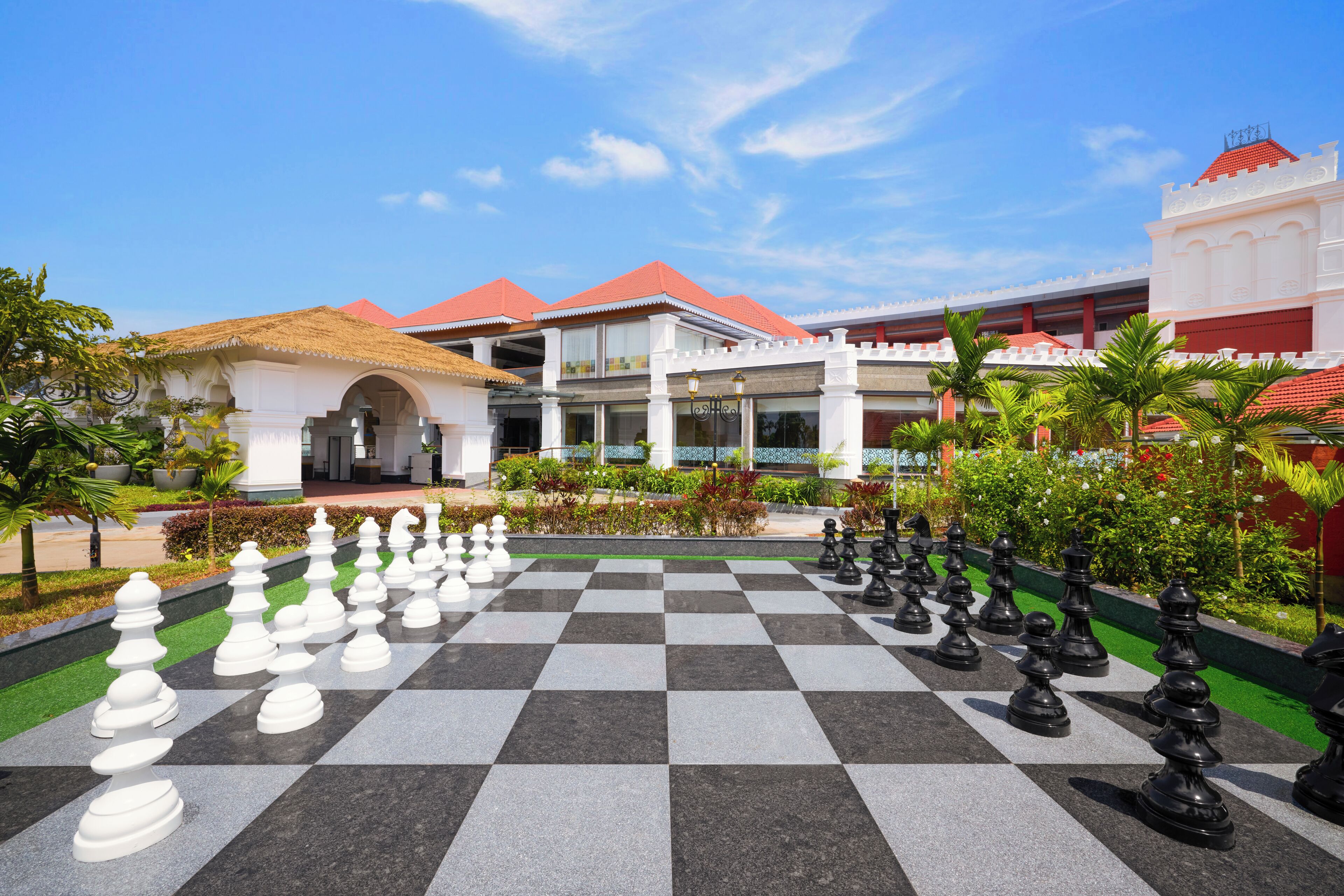 A large outdoor chessboard surrounded by buildings with red roofs and white walls.