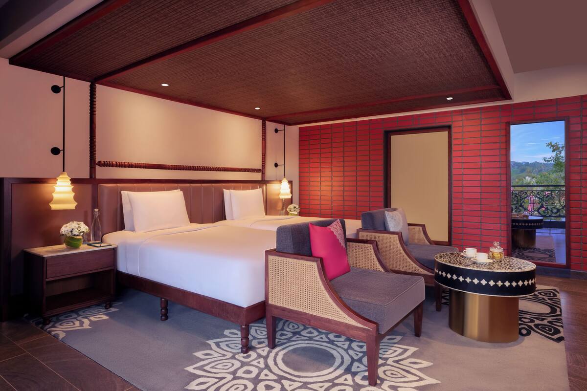 Ein Hotelzimmer mit einem großen Bett, einer Sitzecke mit einem runden Tisch und Blick auf einen Balkon.