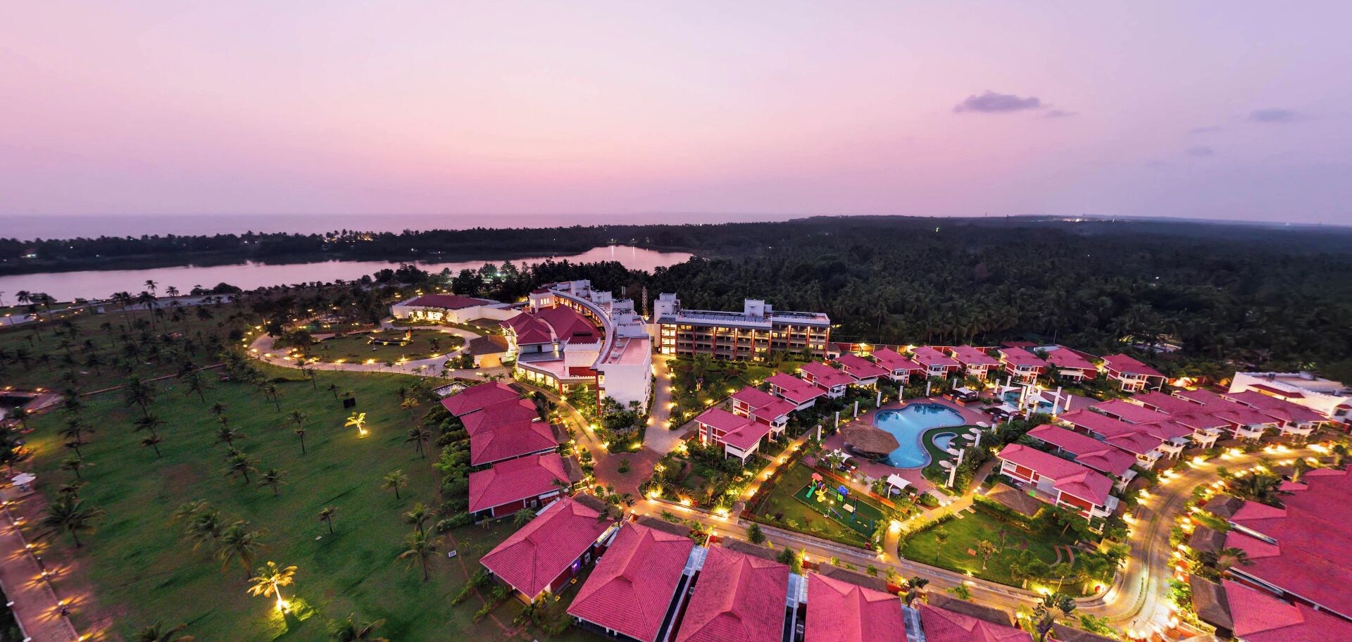 An aerial view of a resort with multiple buildings, a swimming pool, and a large open area with pathways.